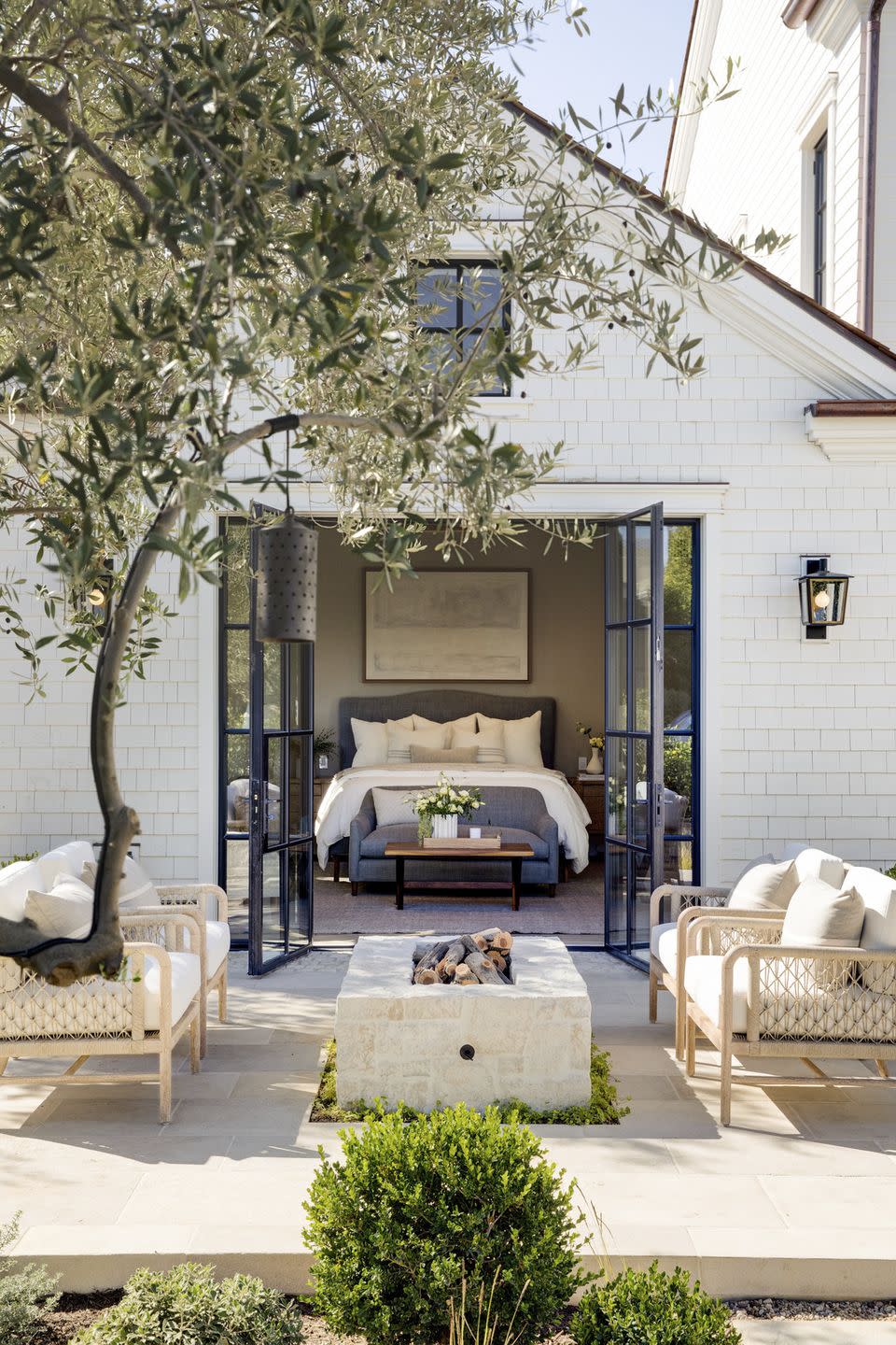 this sandstone patio, just beyond the glass doors of a bedroom by designer brooke wagner, is outfitted with palecek seating and a custom fireplace for enjoying the southern california climate durable, sedimentary rock pavers like these can be sourced in a wide color range to suit any style