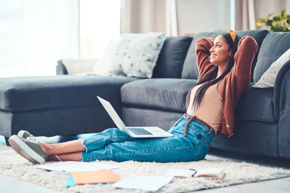 Woman sits back in her living room with her computer on her lap