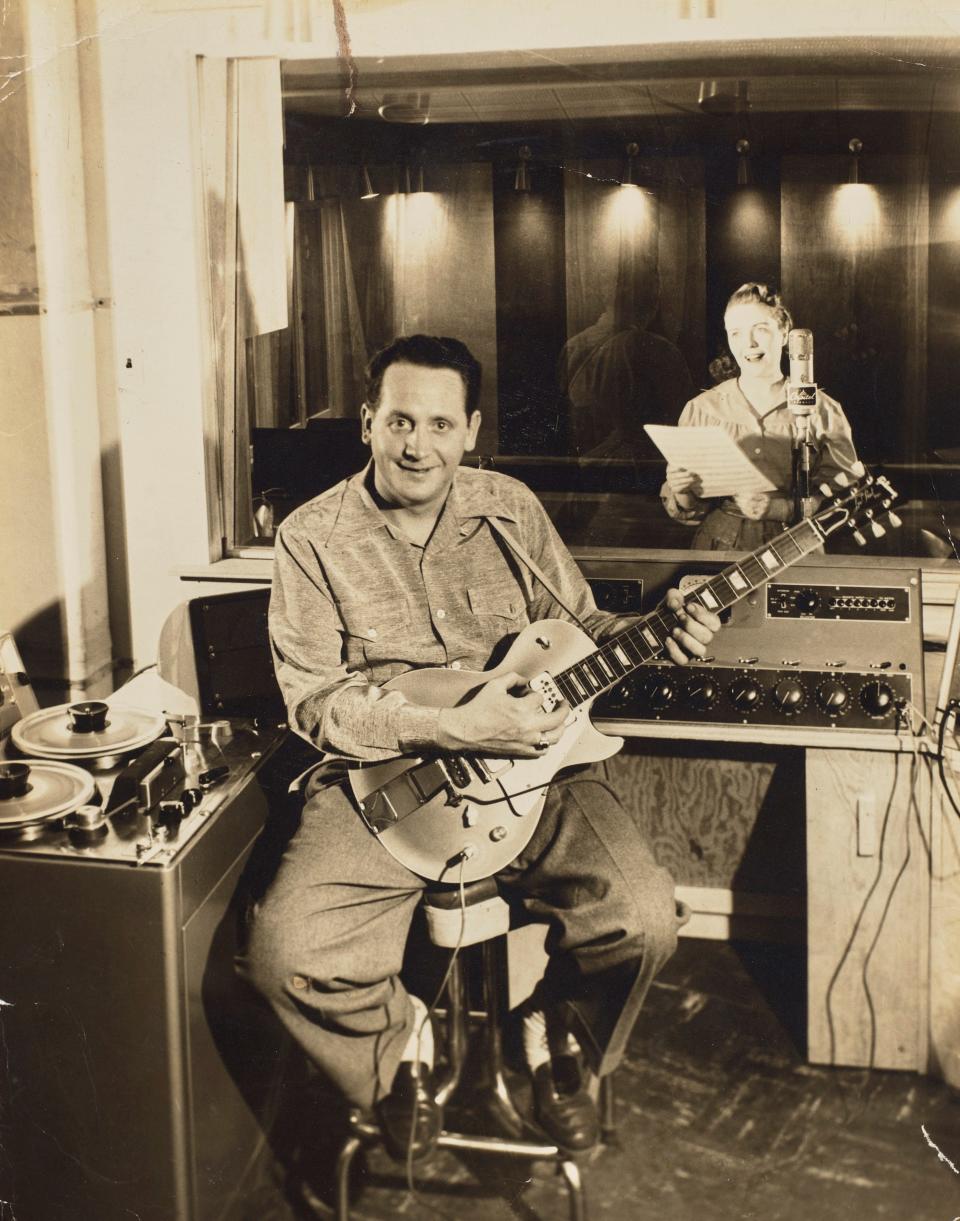 Les Paul holds his "Number One" Les Paul Gibson Goldtop guitar with wife Mary Ford in the background in Paul's recording studio in Mahwah, New Jersey in 1952.