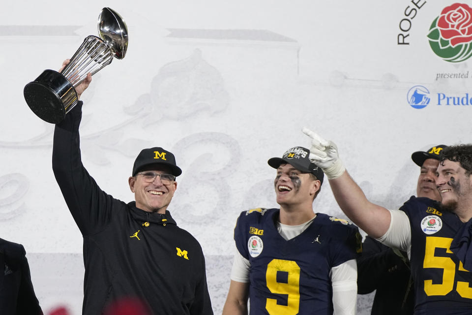 Michigan head coach Jim Harbaugh holds the winner's trophy next to quarterback J.J. McCarthy (9) after a win over Alabama in the Rose Bowl CFP NCAA semifinal college football game Monday, Jan. 1, 2024, in Pasadena, Calif. (AP Photo/Mark J. Terrill)