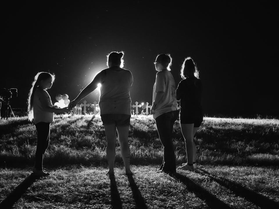 A family stands near 26 crosses set up in a baseball field a few blocks from the site of the shooting during a memorial service in Sutherland Springs, Texas. (Photo: Holly Bailey/Yahoo News)