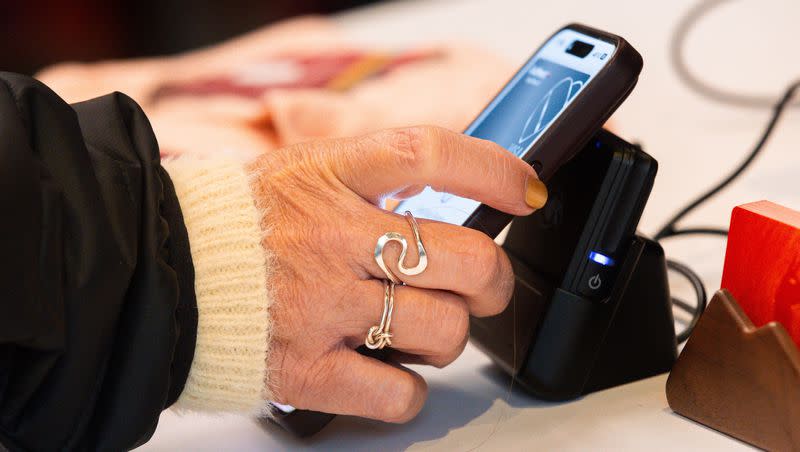 A customer uses Apple Pay to pay for items on Black Friday at Cotopaxi in Salt Lake City on Nov. 24, 2023. Trackers say consumer debt has topped $5 trillion in the U.S.