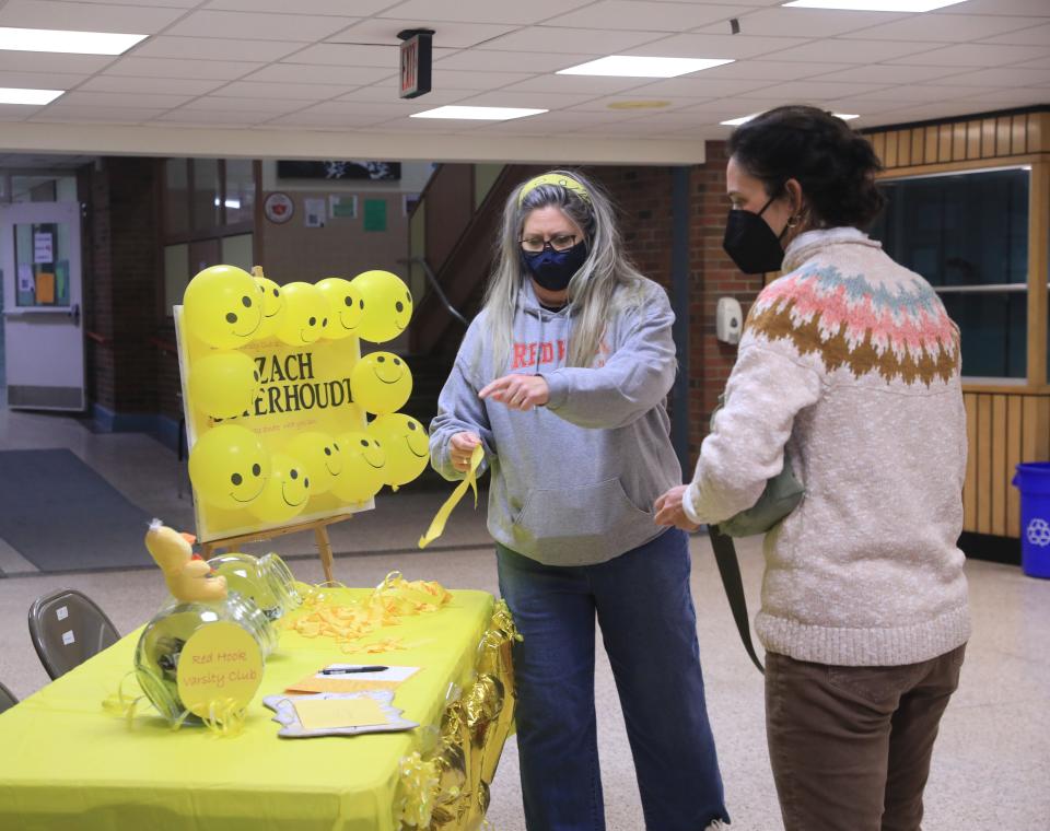 After accepting a donation, Alexandra Brenner asks Maura Sullivan to sign a card for Highland's Zach Osterhoudt before Friday's boys basketball game at Red Hook on February 18, 2022. 