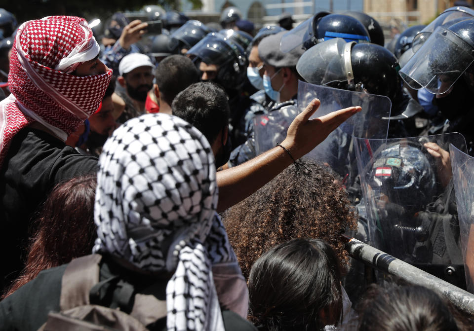 An anti-government protester argues with riot police during a protest against a general amnesty law being proposed in parliament, in Beirut, Lebanon, Thursday, May 28, 2020. (AP Photo/Hussein Malla)