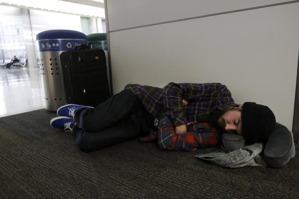 Ezra Allen sleeps while waiting to board a flight to Tampa Bay at San Francisco International Airport in San Francisco, Tuesday, Nov. 26, 2019. Northern California and southern Oregon residents are bracing for a 'bomb cyclone' that's expected at one of the busiest travel times of the year. (AP Photo/Jeff Chiu)