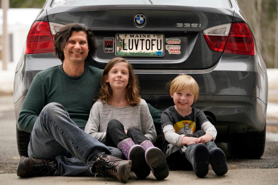 Peter Starostecki and his kids Sadie, center, and Jo Jo, pose behind their car with the vanity license plate that the state of Maine has deemed in appropriate, Wednesday, March 8, 2023, in Poland, Maine (Copyright 2023 The Associated Press. All rights reserved.)