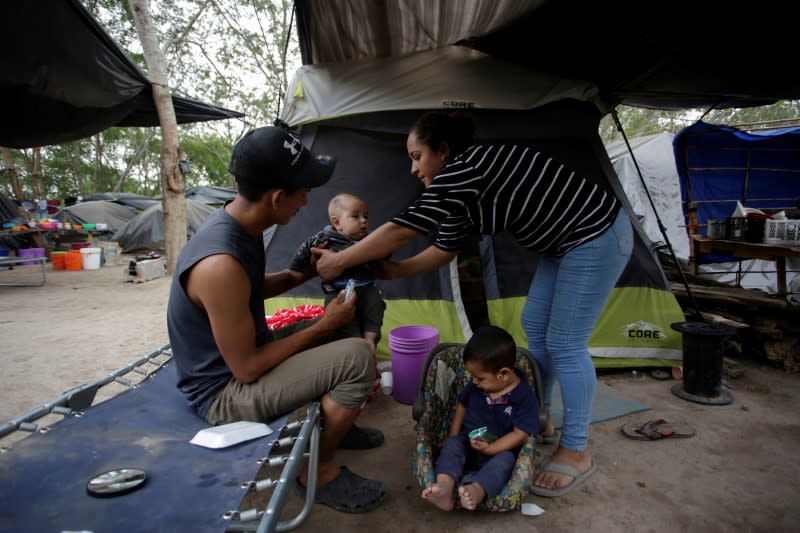 Central American migrants, who are seeking asylum in the U.S., share a moment at an encampment of more than 2,000 migrants, as local authorities prepare to respond to the coronavirus disease (COVID-19) outbreak, in Matamoros