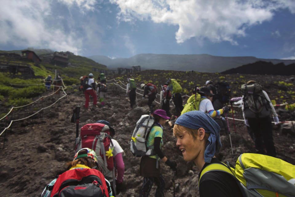 In this Saturday, Aug. 10, 2013 photo, Japanese hikers climb one of the trails on Mount Fuji in Japan. The recent recognition of the 3,776-meter (12,388-foot) peak as a UNESCO World Heritage site has many here worried that will draw still more people, adding to the wear and tear on the environment from the more than 300,000 who already climb the mountain each year. (AP Photo/David Guttenfelder)