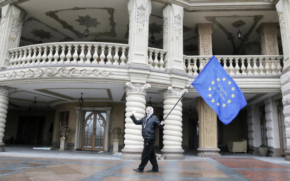 A protester waves an EU flag at the Ukrainian President Yanukovych country residence in Mezhyhirya, Kiev's region, Ukraine, Saturday, Feb, 22, 2014. Viktor Yanukovych is not in his official residence of Mezhyhirya, which is about 20 kilometres north of the capital. Ukrainian security and volunteers from among the Independence Square protesters have joined forces to protect the presidential countryside retreat from vandalism and looting. (AP Photo/Efrem Lukatsky)