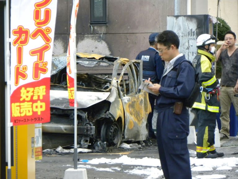 Policemen and firefighters investigate a parking lot after an explosion in Utsunomiya killed one person and at least two injured on October 23, 2016