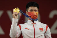 Li Fabin of China celebrates on the podium after winning the gold medal and setting an Olympic record in the men's 61kg weightlifting event, at the 2020 Summer Olympics, Sunday, July 25, 2021, in Tokyo, Japan. (AP Photo/Luca Bruno)
