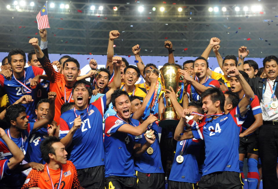 Malaysia's players and officials hold the Suzuki Cup after defeating Indonesia in the final.