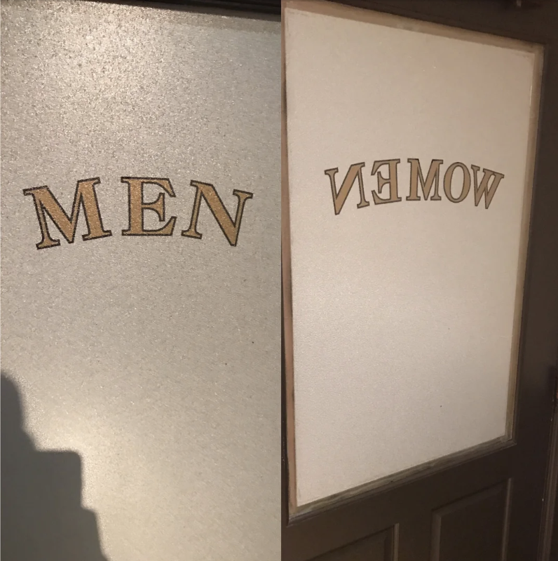 Restroom doors labeled "MEN" and "WOMEN" with the "WOMEN" sign written backwards on one door