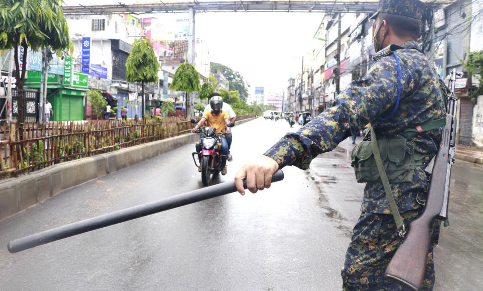 A policeman stops commuters in Rajshahi, 254 kilometers (158 miles) north of the capital, Dhaka, Bangladesh, June 16, 2021. Rajshahi has become one of the latest hotspots for the deadlier delta variant of the coronavirus. Bangladeshi authorities are increasingly becoming worried over the quick spread of coronavirus in about two dozen border districts close to India amid concern that the virus could devastate the crowded nation in coming weeks. (AP Photo/ Kabir Tuhin)