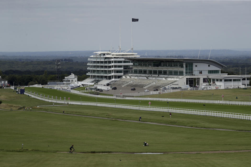 People cycle, walk and sit on the Downs surrounded by the Epsom Downs Racecourse, in Epsom, England, Friday, July 3, 2020. The Derby annual horse race will take place at the Epsom Downs Racecourse behind closed doors on Saturday amid the coronavirus pandemic. (AP Photo/Matt Dunham)