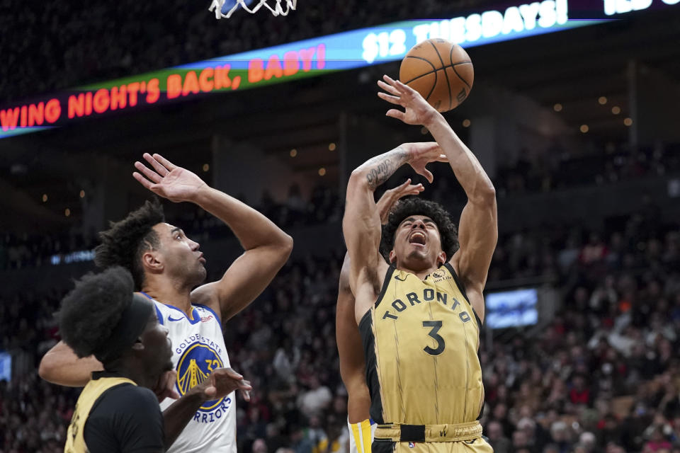Toronto Raptors guard D.J. Carton (3) jumps for the ball while being guarded by Golden State Warriors forward Trayce Jackson-Davis (32) during the second half of an NBA basketball game, in Toronto on Friday, March 1, 2024. (Arlyn McAdorey/The Canadian Press via AP)