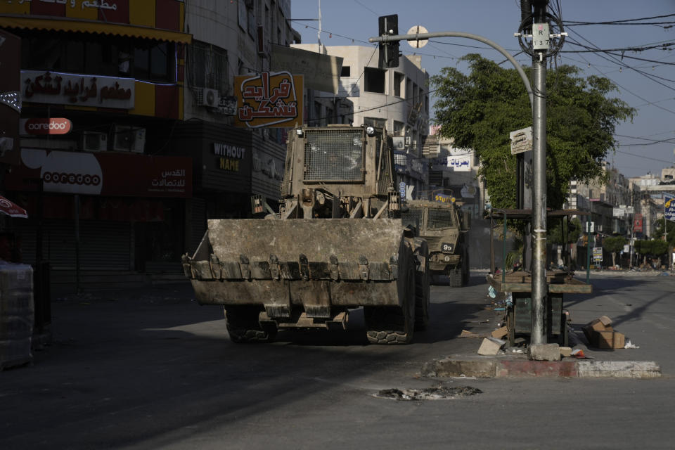 An Israeli bulldozer and an armoured vehicle move on a street during a raid in the West Bank city of Jenin, Thursday, June 6, 2024. The Palestinian Health Ministry says three Palestinians have been killed by Israeli fire in the occupied West Bank. The Israeli military said forces carrying out an arrest raid on Thursday opened fire at three individuals who had thrown explosives at them and that a helicopter struck the area. (AP Photo/Majdi Mohammed)