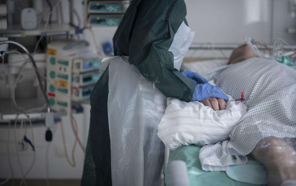 Nursing staff in protective equipment cares for a corona patient in a hospital in Essen, Germany, Wednesday, Oct. 28, 2020. People with a new coronavirus infection are treated in the intensive care unit IT2 in the Operative Centre II of the University Hospital Essen. (Fabian Strauch/dpa via AP)