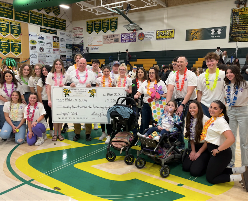 Pueblo County High School students and staff hold up a $22,368 check to the Make-A-Wish Foundation that will help send local six-year-old Poppy Pino and her family to Hawaii.