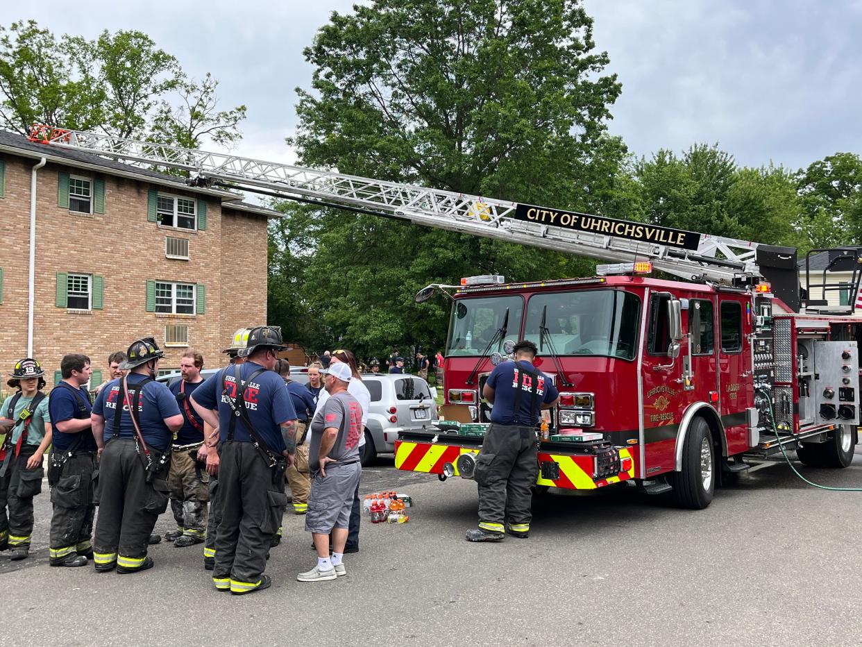 Firefighters gather outside an apartment building at 200 Claymont Drive, Uhrichsville, after a fire damaged apartments on the third floor of the building Sunday morning.