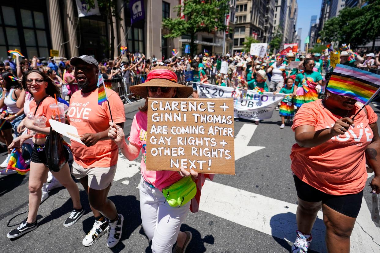 A reveler holds a sign referring to Supreme Court Justice Clarence Thomas and his wife, Ginni, as she marches down Fifth Avenue during the annual NYC Pride March, Sunday, June 26, 2022, in New York. 