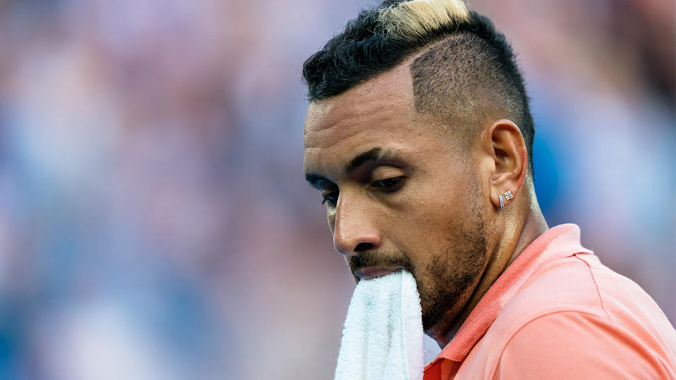 Nick Kyrgios holds his towel in his mouth after a point.