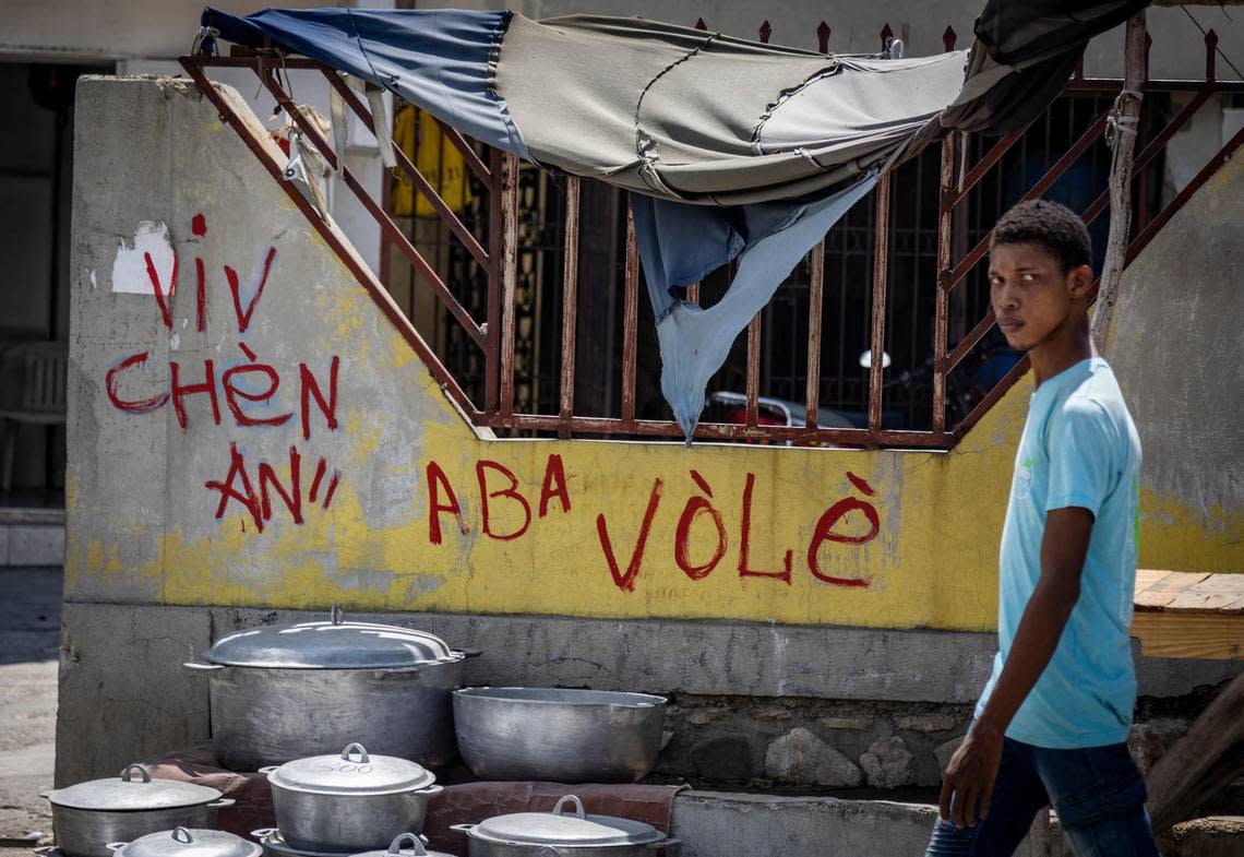 A young man walks by gang-related graffiti near a Haiti National Police checkpoint in Butte-Boyer, which is a stronghold of the gang “Chen Mechan.”