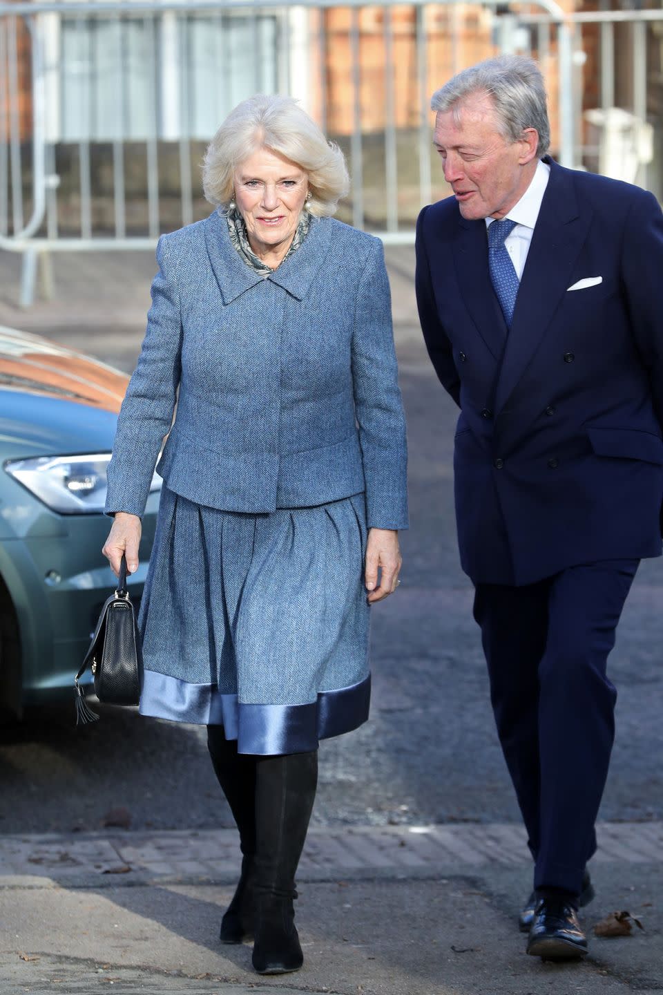 <p>Camilla chose a soft gray-blue skirt suit for a visit to a community center.</p>