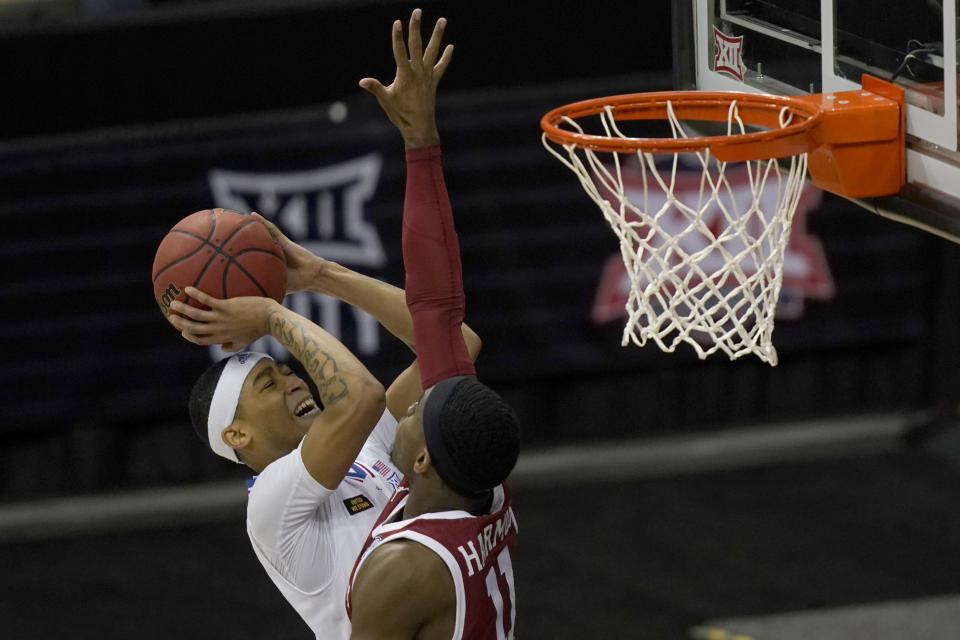Kansas guard Dajuan Harris, left, shoots over Oklahoma guard De'Vion Harmon (11) during the first half of an NCAA college basketball game in the quarterfinal round of the Big 12 men's tournament in Kansas City, Mo., Thursday, March 11, 2021. (AP Photo/Orlin Wagner)