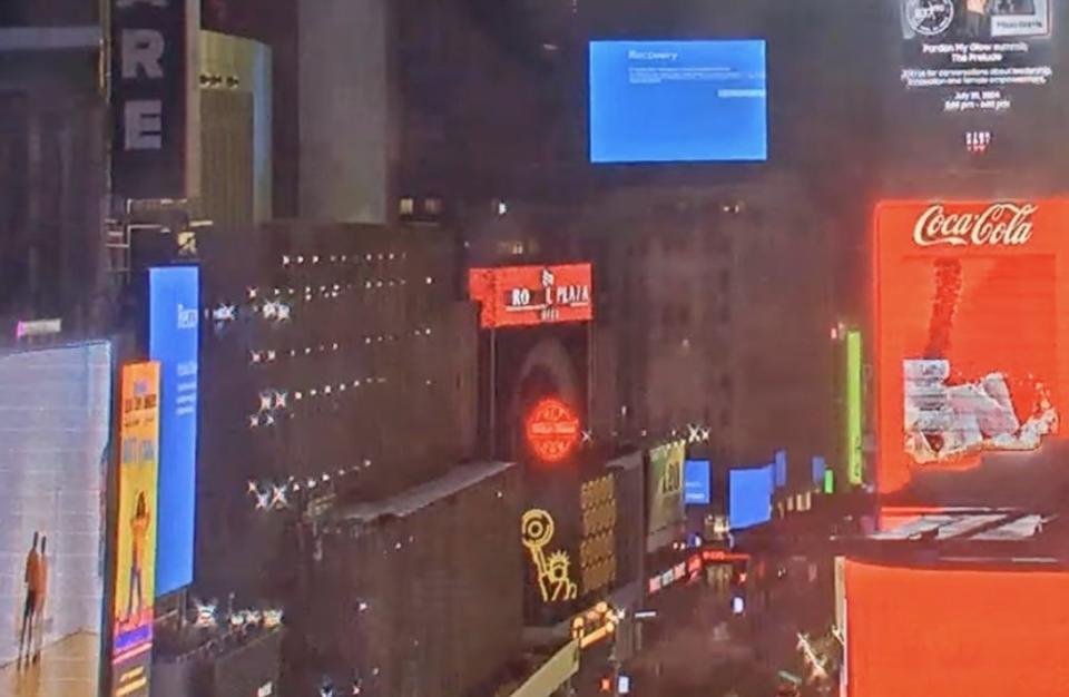Billboards in Times Square at night, with one prominently displaying a "Recovery" message, indicating a malfunction