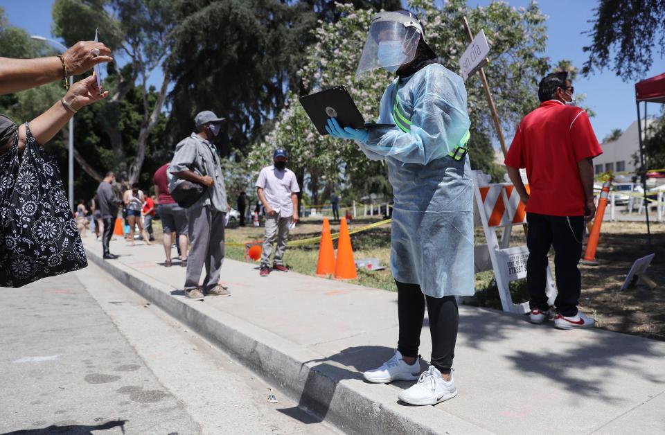 A volunteer helps check in people awaiting testing at a COVID-19 testing center at Lincoln Park amid the coronavirus pandemic on July 7, 2020, in Los Angeles, California. / Credit: Getty