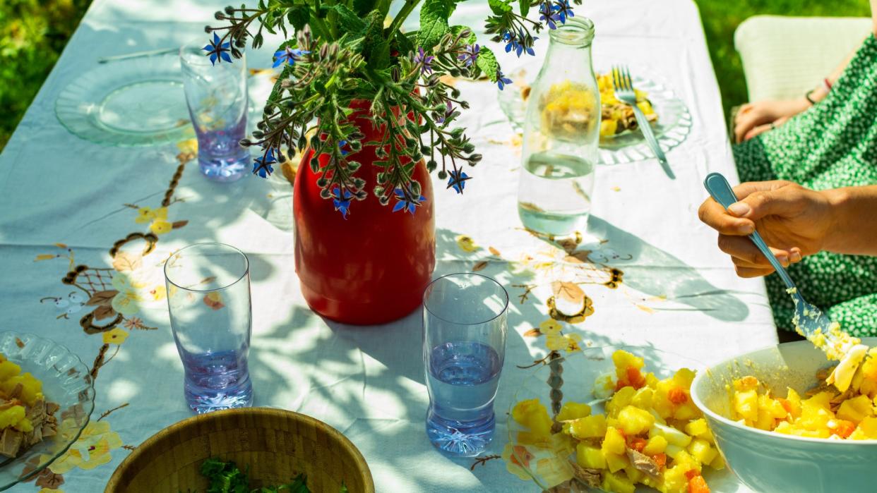  Table with white tablecloth, flowers and food on a spring day. 