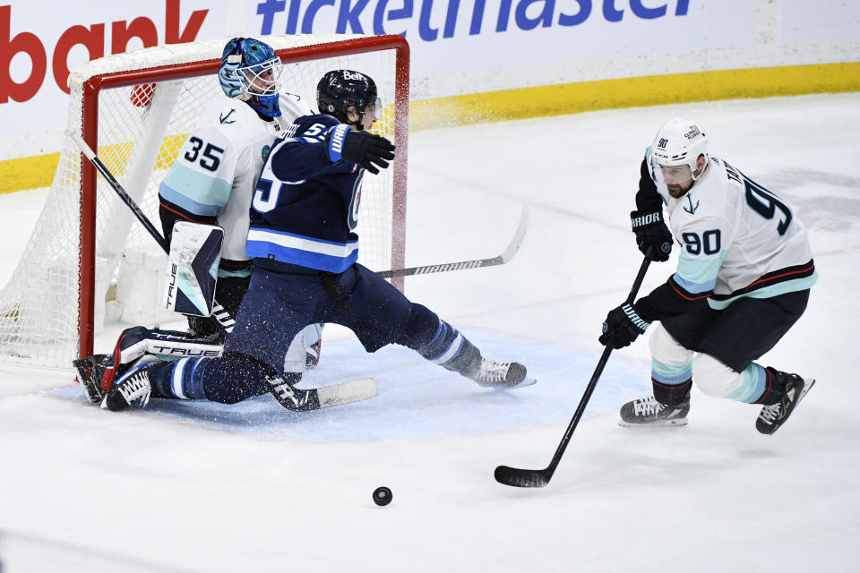 Winnipeg Jets' Mark Scheifele (55) collides with Seattle Kraken goaltender Joey Daccord (35) as Tomas Tatar (90) collects the puck during the third period of an NHL hockey game Tuesday, March 5, 2024, in Winnipeg, Manitoba. (Fred Greenslade/The Canadian Press via AP)