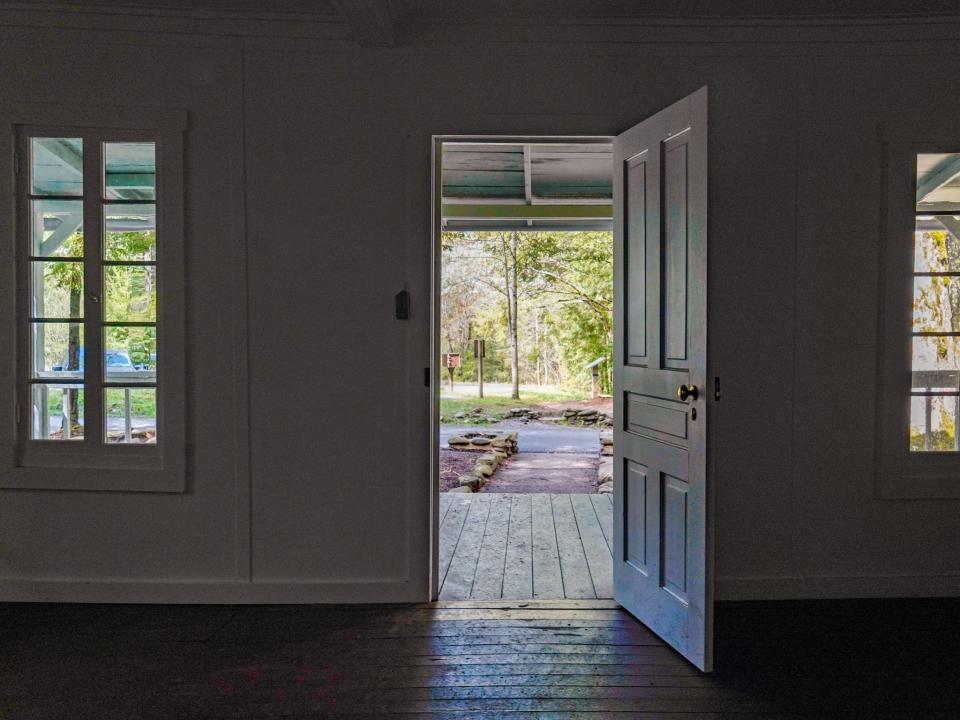 Inside a home with the front door open showing trees outside