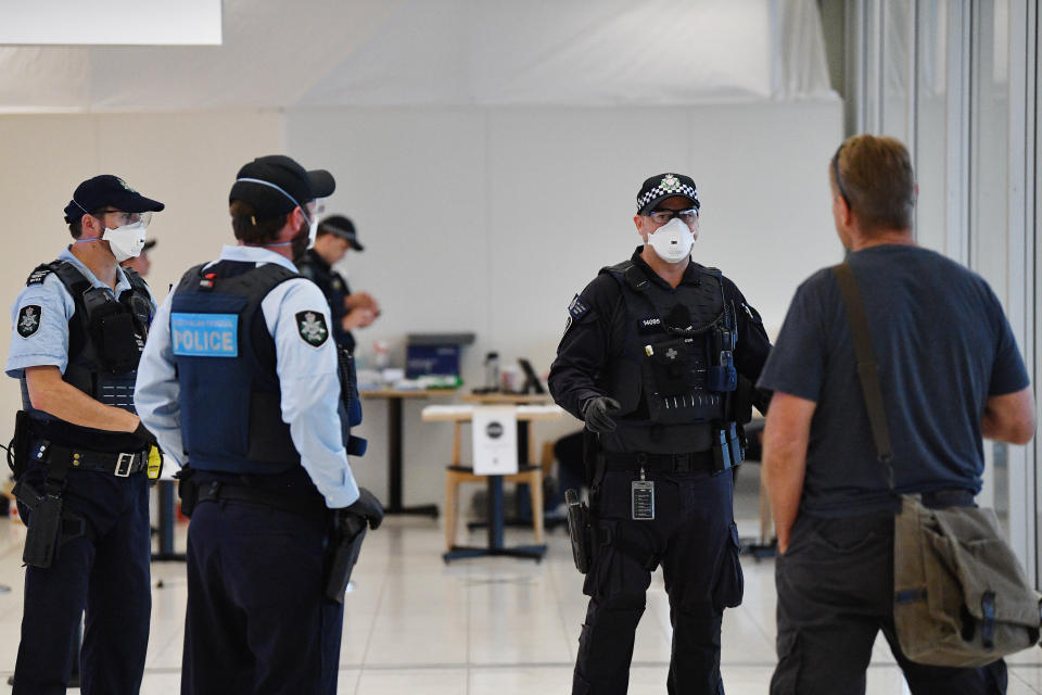 Police wearing face masks are seen at Adelaide Airport. A new plan may see people who breach self-isolation or quarantine forced to wear tracking devices.