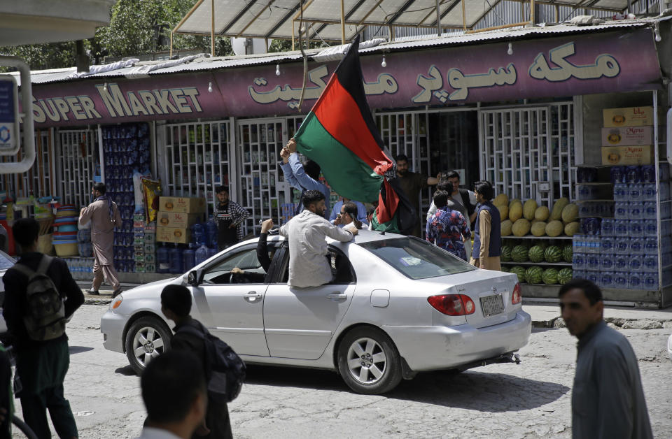 Afghans wave a black, red and green banner in honor of the Afghan flag — a banner that is becoming a symbol of defiance since the Taliban have their own flag, on Afghan Independence Day, in Kabul, Afghanistan, Thursday, Aug. 19, 2020. On Thursday, a procession of cars and people near Kabul's airport carried long black, red and green banners in honor of the Afghan flag — a banner that is becoming a symbol of defiance since the militants have their own flag. (AP Photo/Rahmat Gul)