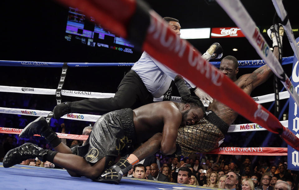 Referee Tony Weeks, left, Deontay Wilder, right, and Bermane Stiverne fall to the mat during the WBC heavyweight championship boxing match Saturday, Jan. 17, 2015, in Las Vegas. (AP Photo/Isaac Brekken)