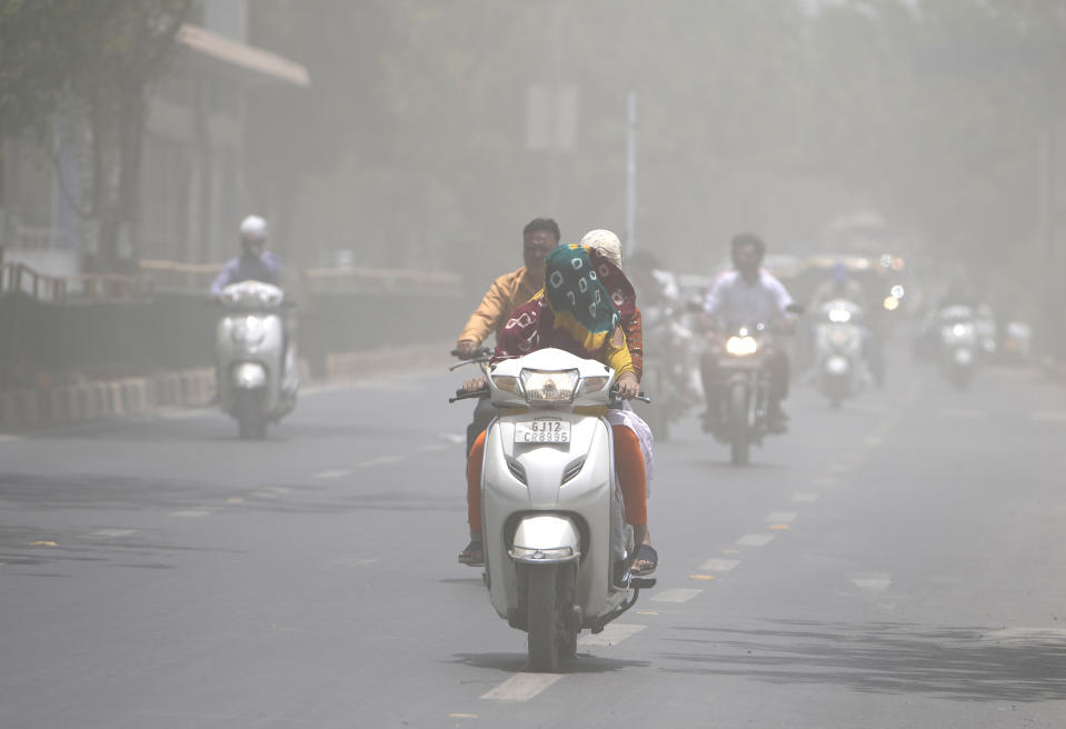 A woman covers her face with a scarf to protect from heat wave rides through a dust storm in Ahmedabad, India, Saturday, May 21, 2022. The intense heat wave sweeping through South Asia was made more likely due to climate change and it is a sign of things to come. An analysis by international scientists said that this heat wave was made 30-times more likely because of climate change, and future warming would make heat waves more common and hotter in the future. (AP Photo/Ajit Solanki)