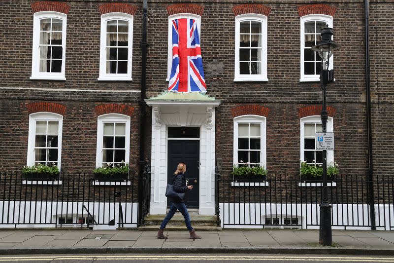 Woman walks past a Union Jack flag hanging on a house in Westminster in London