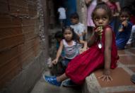 En esta imagen, tomada el 26 de agosto de 2018, una niña sostiene su cuchara mientras espera para recibir la comida en un centro infantil en el vecindario de La Vega, en Caracas, Venezuela. El activista opositor Roberto Patiño dijo que abandonó sus ambiciones políticas para centrarse en alimentar a 1.800 niños cinco días a la semana en 21 barrios pobres capitalinos. (AP Foto/Ariana Cubillos)