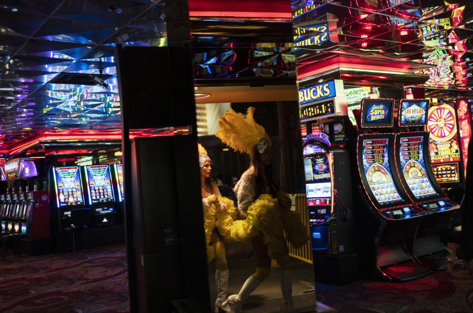 FILE - In this Feb. 10, 2021, file photo, buskers dressed as showgirls walk into a casino along the Las Vegas Strip in Las Vegas. Vaccinated diners, dancers, business owners and bodybuilders will be among those who can go maskless beginning June 1 in the Las Vegas area. County lawmakers on Tuesday, May 18, 2021, adopted Centers for Disease Control and Prevention guidelines and dropped plans to tie business occupancy to COVID-19 vaccination rates. (AP Photo/John Locher, File)