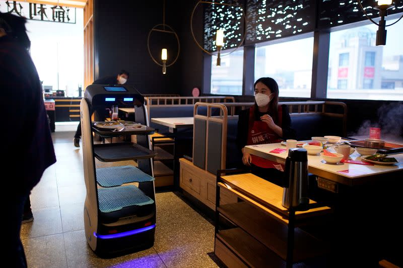 Un robot transporta comida para servirla a los comensales de un restaurante, en Shanghai, China