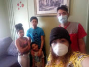 Arely and her husband Rosali, right, take a family photograph with their children Dora, 11, Roberto, 5, and Sirus, 14, after Arely returned from the hospital diagnosed with COVID-19, Thursday May 14 2020, in Baltimore. Having stayed only in her home for months she has no idea how she contracted the virus. (Arely via AP)