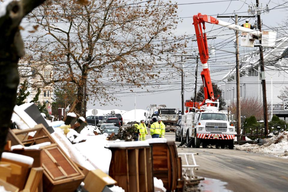 Utility workers the the power lines as snow covered debris from Superstorm Sandy lay on the side of a street following a nor'easter storm, Thursday, Nov. 8, 2012, in Point Pleasant, N.J.  The New York-New Jersey region woke up to wet snow and more power outages Thursday after the nor'easter pushed back efforts to recover from Superstorm Sandy, that left millions powerless and dozens dead last week. (AP Photo/Julio Cortez)