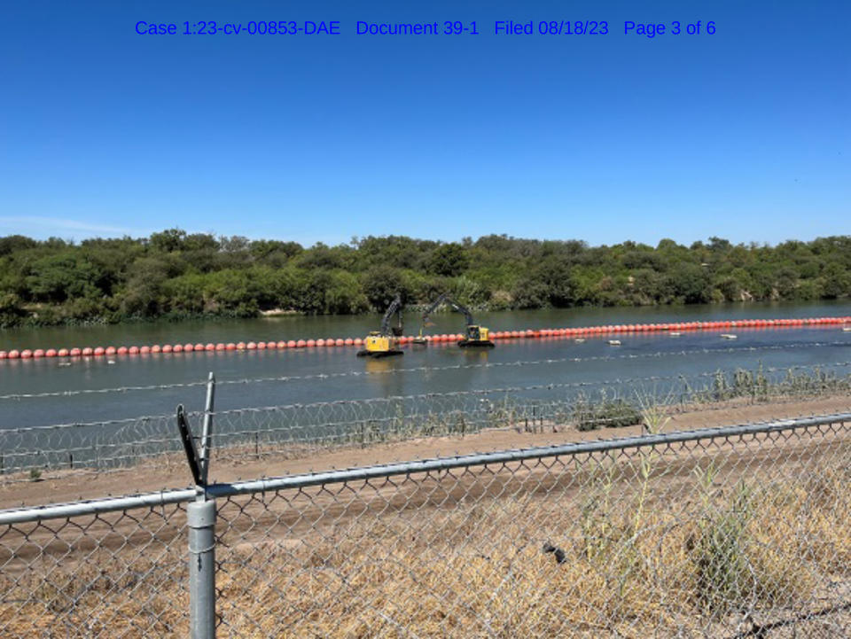 Two excavators next to orange buoys in the Rio Grande river. (via Dept. of Justice)