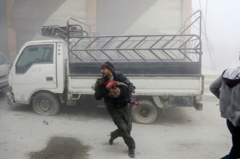 A man carries a child as he flees from reported Syrian air strikes in rebel-held Eastern Ghouta on February 6, 2018