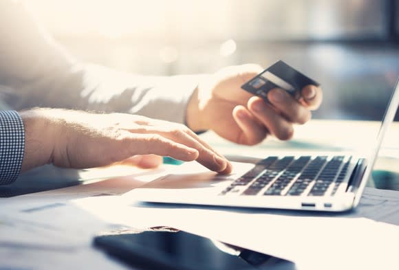 A man enters his credit card information on a laptop