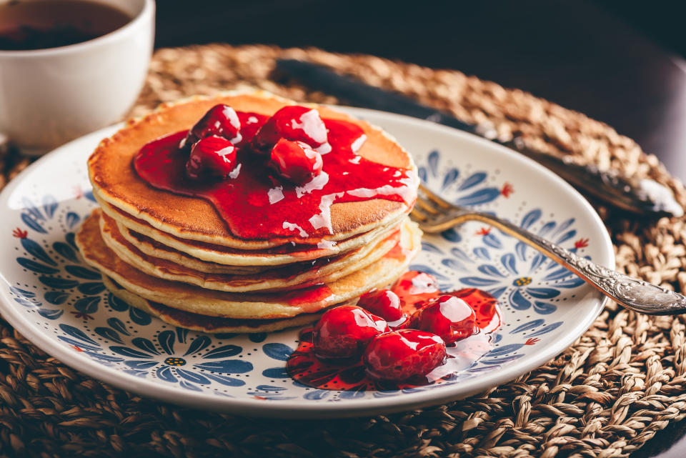 Stack of pancakes with dogberry jam on white plate with ornate