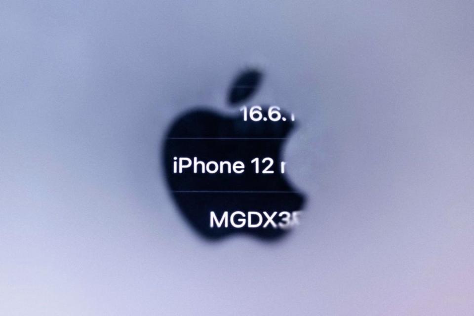 A photograph taken on 13 September, 2023 in Paris shows information of an iPhone 12 reflected in the Apple logo, as French regulators ordered Apple to halt sales for emitting too much electromagnetic radiation (Getty Images)