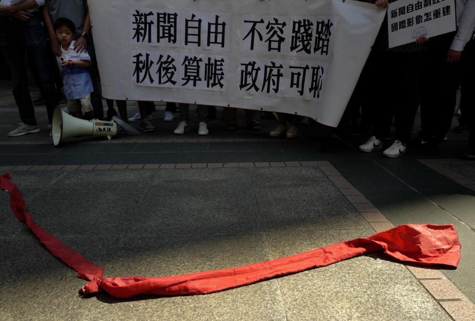 Protesters carry a banner with Chinese reads "Do not trample on press freedom" next to a red ribbon symbolizing the bottom line of the Chinese Communist Party during a protest in Hong Kong, Saturday, Oct. 6, 2018. The protesters staged a rally against Hong Kong's government has refused to renew the work visa of Victor Mallet, a senior editor of the Financial Times, in what human rights activists say is the latest sign of a deteriorating human rights situation in the semi-autonomous Chinese territory. (AP Photo/Vincent Yu)